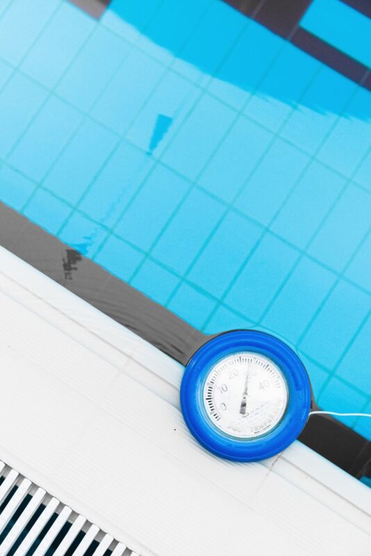 A bottle of Aqualite Chlorine and HTH Dry Acid beside a pool with clear water, showing pool chlorine price in Nairobi.
