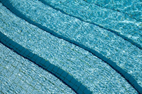A damaged pool pipe next to pure Aqualite chlorine, illustrating how cheap pool chemicals in Nairobi lead to costly plumbing