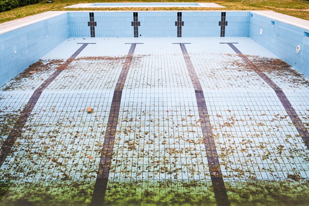 A sparkling blue swimming pool with clear water and pool maintenance tools nearby.